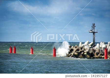 Red Buoys and Breakwater With Waves Crashing Against Concrete Tetrapods and Navigation Light Red Buoys and Breakwater With Waves Crashing Against Concrete Tetrapods and Navigation Light 141957127