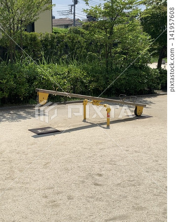 公園裡,綠樹環繞,一座黃色蹺蹺板 公園裡,綠樹環繞,一座黃色蹺蹺板 141957608