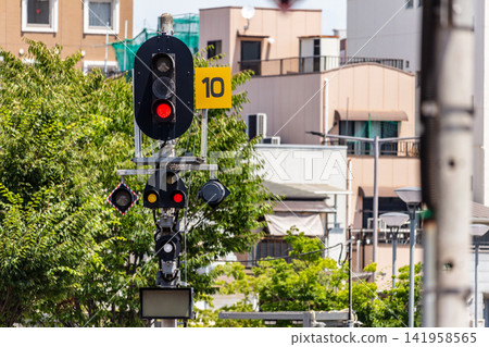 A railway signal light with a red light on, and the cityscape. A railway signal light with a red light on, and the cityscape. 141958565