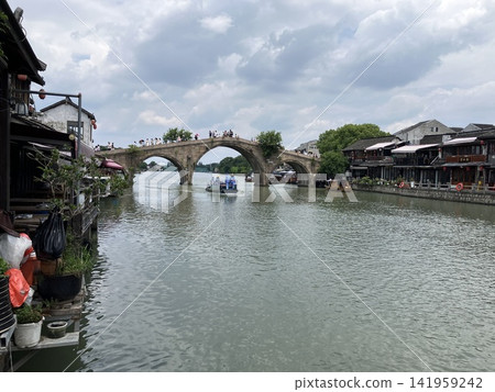 An ancient stone arch bridge spanning a canal in a traditional water town in China. An ancient stone arch bridge spanning a canal in a traditional water town in China. 141959242