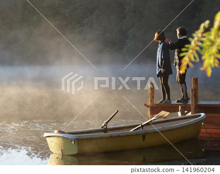 People gazing at the light rising through the morning mist on the lakeshore People gazing at the light rising through the morning mist on the lakeshore 141960204