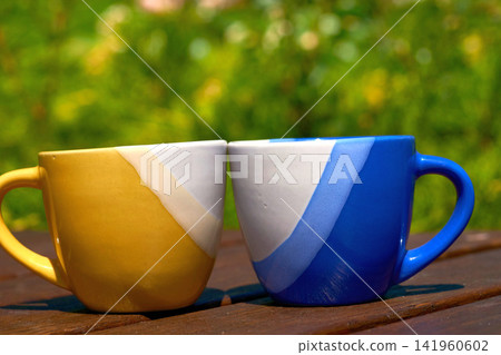 Yellow blue cups on sunny meadow.Coffee break,tea time Yellow blue cups on sunny meadow.Coffee break,tea time 141960602