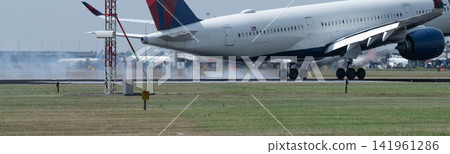 Close-up of passenger aircraft touching down at Amsterdam Schiphol with runway tire smoke and heat haze Close-up of passenger aircraft touching down at Amsterdam Schiphol with runway tire smoke and heat haze 141961286