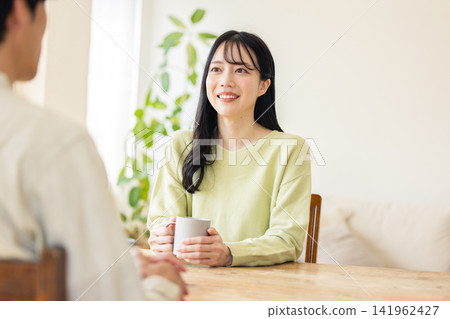 A smiling woman listening attentively to the other person, nodding gently. A smiling woman listening attentively to the other person, nodding gently. 141962427