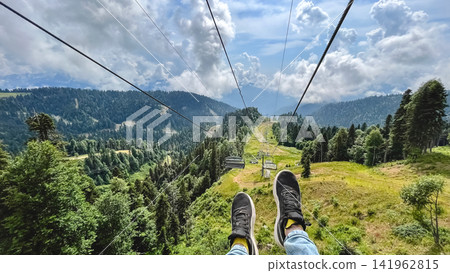 Mountain chairlift over lush green alpine landscape Mountain chairlift over lush green alpine landscape 141962815