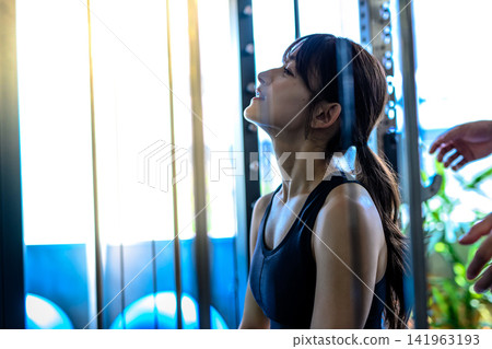 A woman sits on a Smith machine, regulating her breathing, receiving instructions from a trainer at the gym. Morning color art dimming. A woman sits on a Smith machine, regulating her breathing, receiving instructions from a trainer at the gym. Morning color art dimming. 141963193