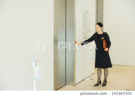 一位女士引導人們前往電梯。 一位女士引導人們前往電梯。 141963505