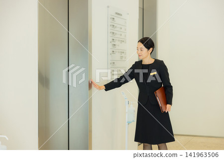 A woman guiding people to the elevator A woman guiding people to the elevator 141963506