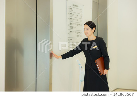 A woman guiding people to the elevator A woman guiding people to the elevator 141963507