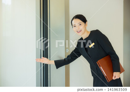 一位女士引導人們前往電梯。 一位女士引導人們前往電梯。 141963509