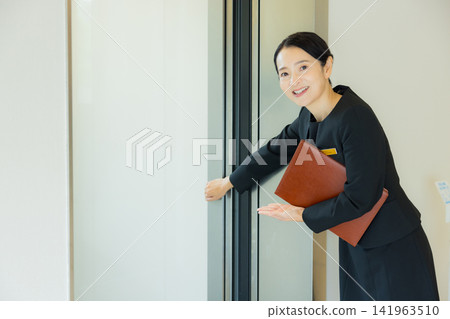 A woman guiding people to the elevator A woman guiding people to the elevator 141963510
