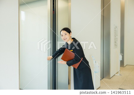A woman guiding people to the elevator A woman guiding people to the elevator 141963511