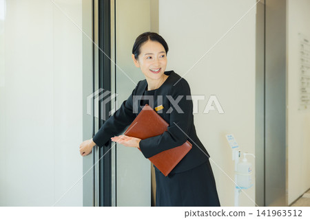 A woman guiding people to the elevator A woman guiding people to the elevator 141963512
