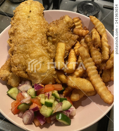 Crispy golden fish paired with thick-cut fries, offering a perfect balance of crunchy batter and tender, flaky meat. A warm, comforting dish great for cozy meals and inviting food photography. Crispy golden fish paired with thick-cut fries, offering a perfect balance of crunchy batter and tender, flaky meat. A warm, comforting dish great for cozy meals and inviting food photography. 141963654