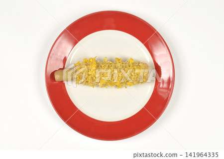 Eaten corn cob on a red plate from above Eaten corn cob on a red plate from above 141964335