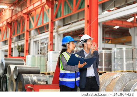 Industrial engineers and manager inspecting manufacturing process in steel factory warehouse. Industrial engineers and manager inspecting manufacturing process in steel factory warehouse. 141964428