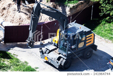 Heavy construction excavator at work on construction site, moving earth and dirt, powerful machinery for building development, industrial equipment for digging operations 141964744