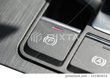 Close-up view modern car electronic parking brake button P symbol illuminated red indicator light, showing part auto-hold button on brushed metal dashboard. Close-up view modern car electronic parking brake button P symbol illuminated red indicator light, showing part auto-hold button on brushed metal dashboard. 141964814
