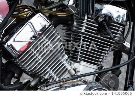 Close up of motorcycle engine power unit detail featuring shiny chrome, cooling fins, cables, and various mechanical components, showcasing rugged automotive engineering and robust design Close up of motorcycle engine power unit detail featuring shiny chrome, cooling fins, cables, and various mechanical components, showcasing rugged automotive engineering and robust design 141965006