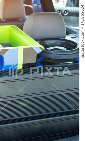 Powerful custom car audio system installation with vibrant green, blue, black enclosure and large subwoofer in vehicle trunk, showcasing detail of modern amplifier for high fidelity sound. Powerful custom car audio system installation with vibrant green, blue, black enclosure and large subwoofer in vehicle trunk, showcasing detail of modern amplifier for high fidelity sound. 141965024