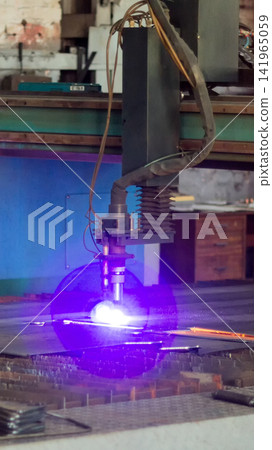 Plasma cutting machine in industrial workshop producing vibrant purple light during high-precision operation on metal sheet with intense sparks, showing modern manufacturing process vertical photo Plasma cutting machine in industrial workshop producing vibrant purple light during high-precision operation on metal sheet with intense sparks, showing modern manufacturing process vertical photo 141965059