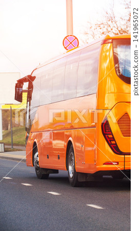Bright orange passenger bus driving on road, rear view of vehicle exterior, modern design transportation, city street scene, urban mobility infrastructure, vertical photo Bright orange passenger bus driving on road, rear view of vehicle exterior, modern design transportation, city street scene, urban mobility infrastructure, vertical photo 141965072