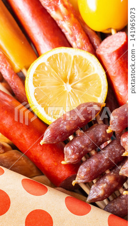 Assortment of gourmet dry cured sausages and meats with fresh lemon slice and yellow fruit, rustic food presentation, close up view vertical photo Assortment of gourmet dry cured sausages and meats with fresh lemon slice and yellow fruit, rustic food presentation, close up view vertical photo 141965073