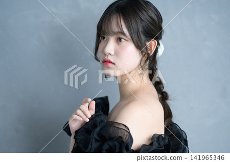 A Japanese woman in a black dress against a gray background. A Japanese woman in a black dress against a gray background. 141965346