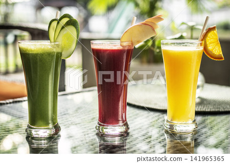 mixed fresh fruit juice glasses on outdoor garden cafe table in sunny summer day 141965365