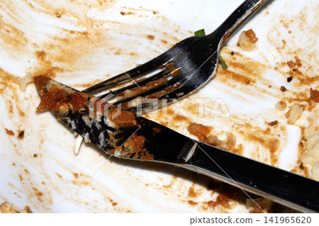 Close up of a messy dirty used white plate with cutlery on Close up of a messy dirty used white plate with cutlery on 141965620