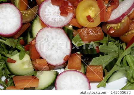Close up of a delicious healthy side salad with leaves and radish on a white plate Close up of a delicious healthy side salad with leaves and radish on a white plate 141965623