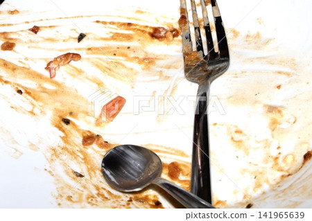 Close up of a messy dirty used white plate with cutlery on 141965639