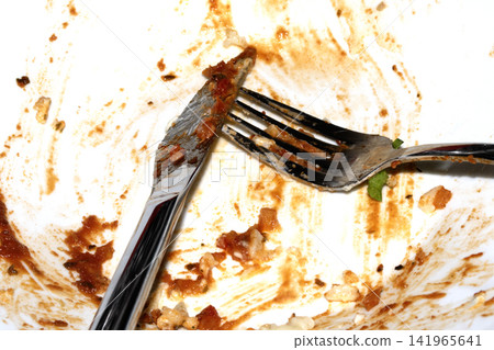 Close up of a messy dirty used white plate with cutlery on Close up of a messy dirty used white plate with cutlery on 141965641