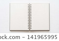 Open blank spiral wirebound sketchbook resting flat upon white wooden desktop background ready for creative writing drawing or daily educational school assignments 141965995