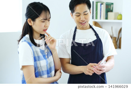 Kitchen: Image of a man and woman thinking up recipes on their smartphones. Kitchen: Image of a man and woman thinking up recipes on their smartphones. 141966029