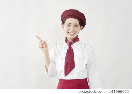 A female pastry chef points to the left. A female pastry chef points to the left. 141966063
