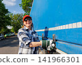 Portrait young adult smiling woman truck driver secures cargo tarp trailer truck  cargo vehicle. Female person girl professional job career working driving freight engine lorry. Logistics industry 141966301