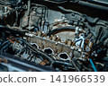 Detailed close-up of modern car engine components with wires, pipes and technical parts under the open hood, auto repair 141966539