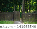 Rustic wooden fence with an open gate leading into a lush green public park, inviting landscape concept 141966540
