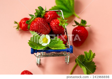 Fresh strawberries in miniature shopping cart on pink background Fresh strawberries in miniature shopping cart on pink background 141966698