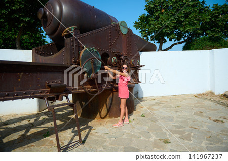 Girl posing on historic cannon at seaside fort on a sunny summer day 141967237