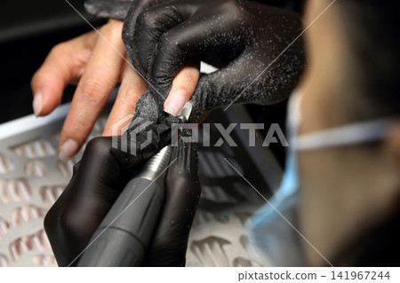 A woman's hand during a manicure. A woman getting a manicure. A manicurist is doing a client's nails at a nail salon. Manicure services. Nail art. Beauty salon. A woman's hand during a manicure. A woman getting a manicure. A manicurist is doing a client's nails at a nail salon. Manicure services. Nail art. Beauty salon. 141967244