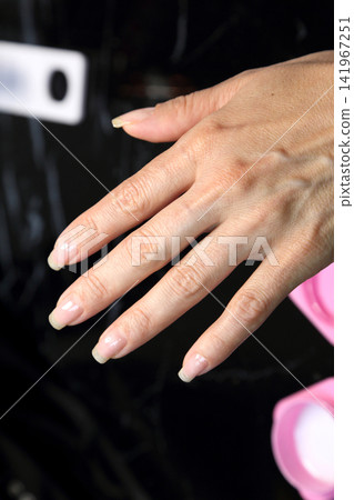 Receiving Professional Manicure in Modern Salon. Beautiful, well-groomed women's hands with elegant nails against a dark background. Beauty salon concept: manicures, pedicures. Receiving Professional Manicure in Modern Salon. Beautiful, well-groomed women's hands with elegant nails against a dark background. Beauty salon concept: manicures, pedicures. 141967251