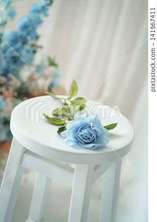 Light blue rose flower lying on white wooden stool in bright interior Light blue rose flower lying on white wooden stool in bright interior 141967411
