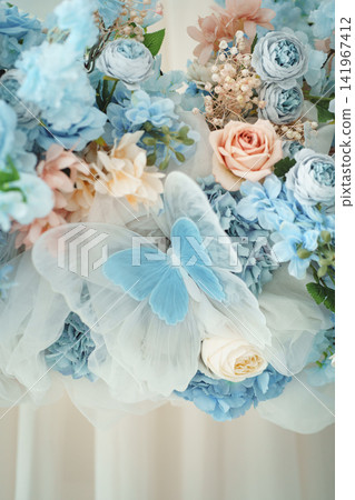 Light blue and pastel pink floral arrangement with decorative butterfly wings on light background Light blue and pastel pink floral arrangement with decorative butterfly wings on light background 141967412