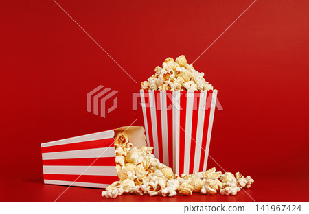 Horizontal layout of spilled popcorn on solid red background. Food photography with copy space. Horizontal layout of spilled popcorn on solid red background. Food photography with copy space. 141967424