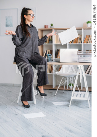 Carefree business manager. Paperwork routine. Relaxed woman professional throwing away papers at desk at modern office. Carefree business manager. Paperwork routine. Relaxed woman professional throwing away papers at desk at modern office. 141967464