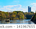A pleasure boat cruising the moat of Osaka Castle, surrounded by colorful trees and the cityscape. 141967655