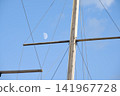 Sailboat mast with daytime moon against clear blue sky 141967728