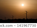 Power lines silhouetted against glowing sunset sky 141967730